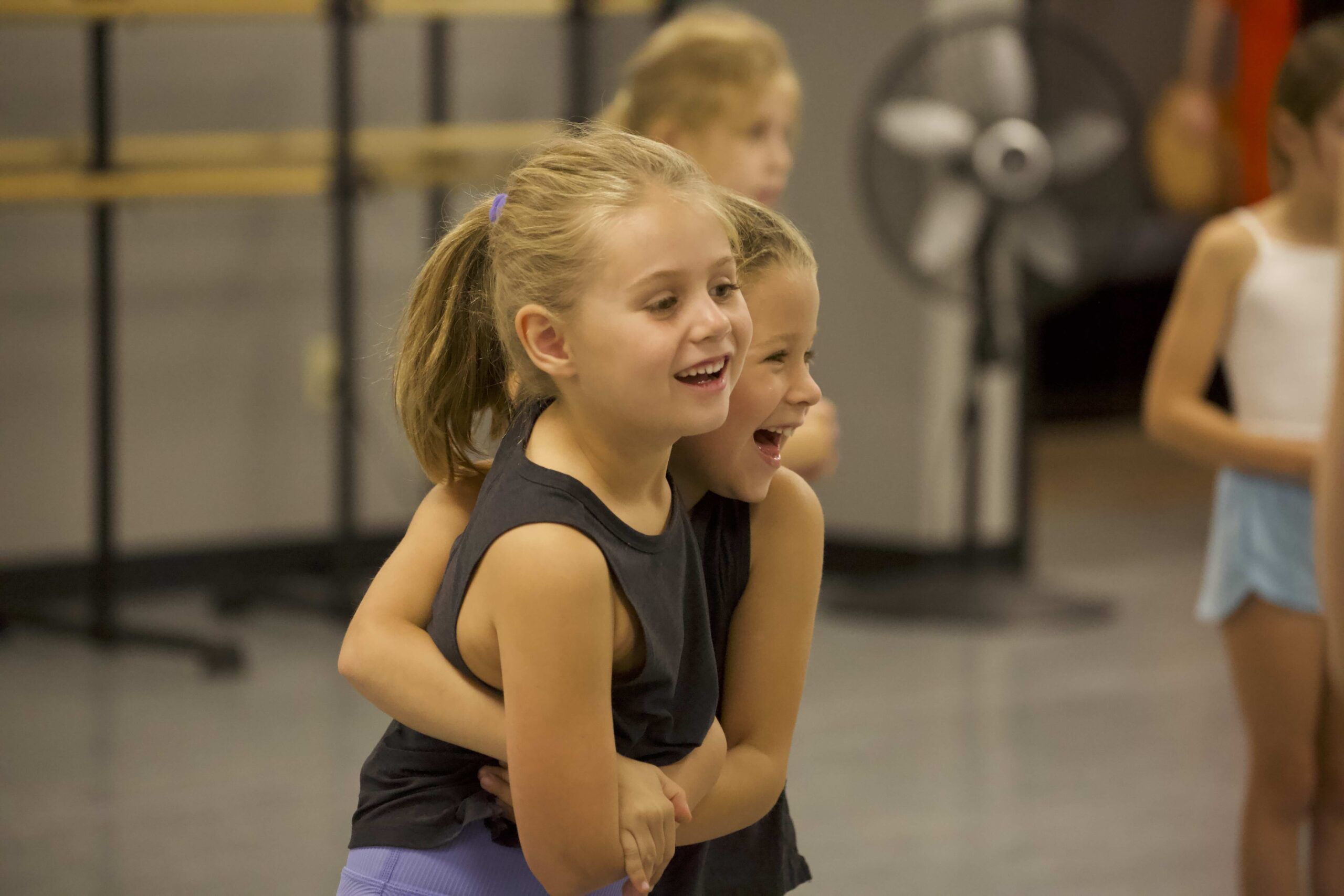two student dancers embracing with smiles on their faces